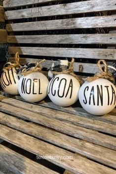 three white painted pumpkins sitting on top of a wooden bench next to each other