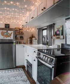 a kitchen with white cabinets and lights hanging from the ceiling over the stove top oven