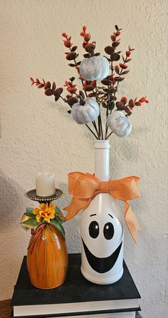 a white vase with a smiley face on it next to a pumpkin and some flowers