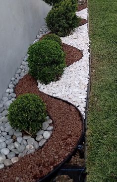 a small garden with rocks and plants in the grass next to a fenced off area