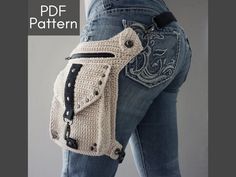 a woman wearing jeans and holding a crocheted purse in the shape of a jacket