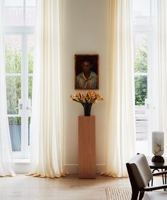 a living room with white curtains and a painting on the wall