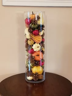 a glass vase filled with lots of different types of fruits and vegetables on top of a wooden table