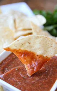 a tortilla chip being dipped with salsa