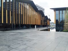 an empty walkway in front of a building with wooden slats on the walls and windows