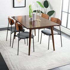 a dining table with four chairs and a plant in the corner on top of it