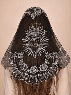 the back of a woman's head with an embroidered veil over her face and cross on it