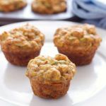 several muffins on a white plate sitting on a wooden table