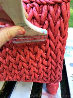 a person is painting a red basket with white paint on the outside and inside it