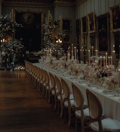 the long table is set with white flowers and candles in front of an ornately decorated wall