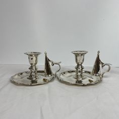 two silver candlesticks sitting on top of each other