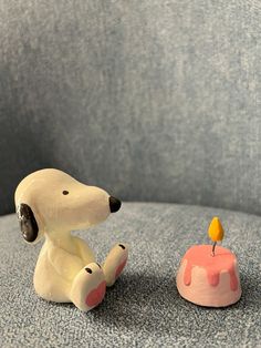 a dog figurine sitting next to a small cake with a candle on it