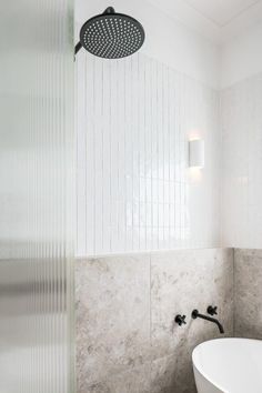 a white bathtub sitting next to a shower head in a bathroom under a light