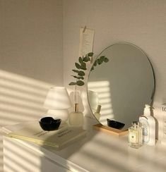 a white dresser topped with a mirror next to a lamp