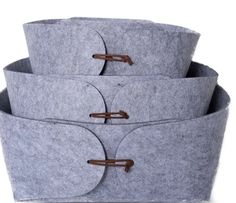 three grey felt storage baskets stacked on top of each other with leather handles and straps