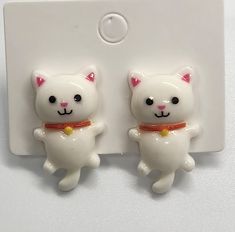 two white cats with red collars are sitting on a hook - up plate,