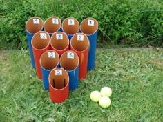 several cups with numbers on them sitting in the grass next to an apple and two tennis balls