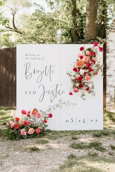 a wedding sign with flowers and greenery on it