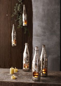 several silver vases and candles on a table