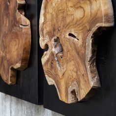 two wooden masks are hanging on the wall next to each other and one is made out of wood