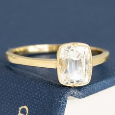 an engagement ring with a large white diamond in the center on top of a blue book