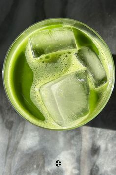 a green drink with ice cubes in it