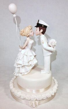 a wedding cake topper with a bride and groom kissing on the cheek, holding balloons