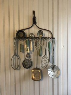 a rack with various kitchen utensils hanging from it's side on a wall