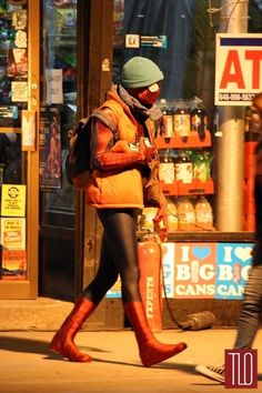 a woman walking down the street in red boots