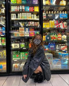 a woman sitting on the ground in front of a refrigerator covered in bottles and cans