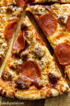 a pepperoni pizza cut into four slices on a wooden cutting board with a spatula