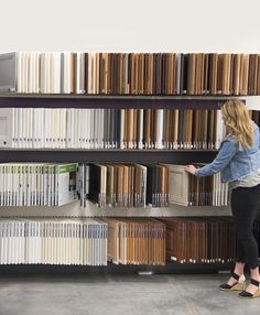 a woman standing in front of a bookshelf filled with lots of different colored books