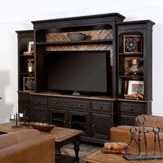 an entertainment center with leather couches and a flat screen tv mounted on the wall