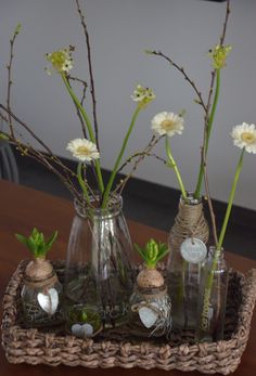 three vases with flowers in them sitting on a table next to bottles and coins