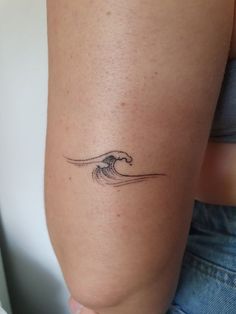 a woman's arm with a small wave tattoo on it