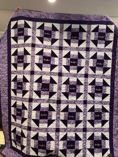 a purple and white quilt on display in a room