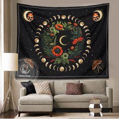 a living room with a couch and a large tapestry on the wall above it that has an image of a crescent moon surrounded by flowers