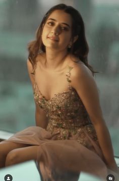 a woman sitting on top of a window sill wearing a dress and smiling at the camera