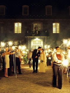 a group of people holding sparklers in front of a building