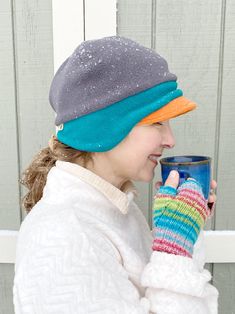 a woman wearing a hat and mitt holding a coffee cup in front of her face