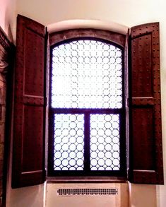 an open window with wooden shutters in front of it