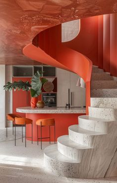 an orange and white spiral staircase in a modern home with marble steps leading up to the kitchen