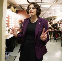 a woman standing in front of a mirror with her hands up and two fingers out