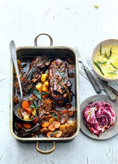 a roasting pan filled with meat and veggies next to a bowl of soup