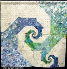 a quilted wall hanging with blue, green and white designs on the bottom half