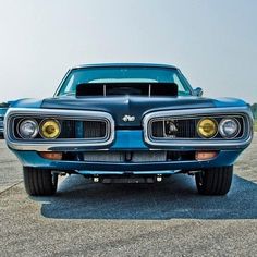 an old blue muscle car parked in a parking lot