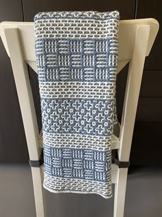 a blue and white blanket sitting on top of a wooden chair