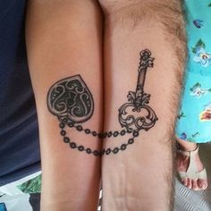 two people that have tattoos on their legs and one has a key to each other