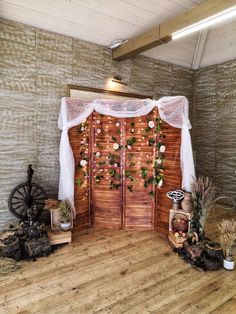 a room with wooden floors and white drapes on the wall, decorated with flowers