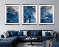 a living room with blue couches and two paintings on the wall above each sofa